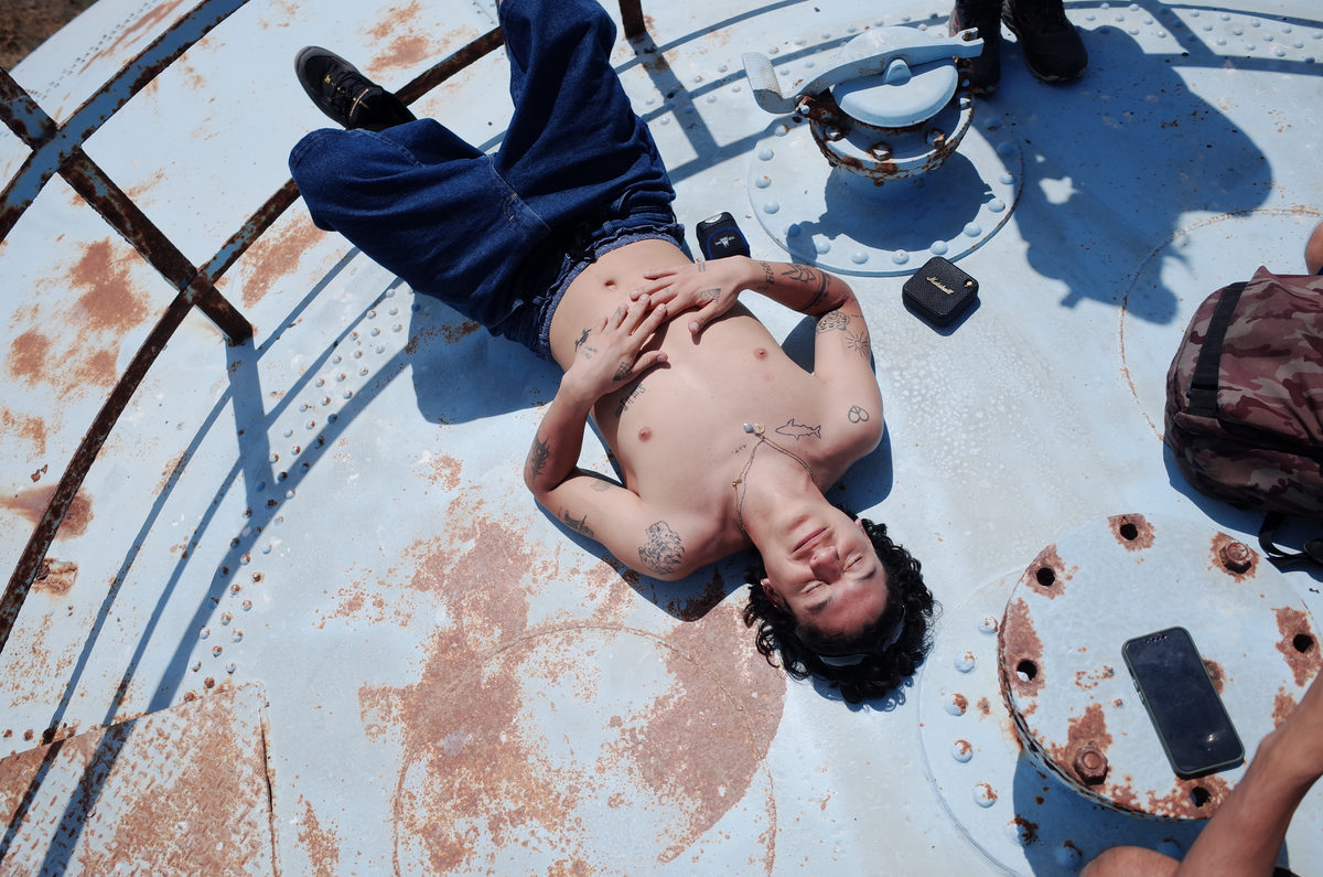 Looking down at a person resting on a rusted metal platform with gear scattered around