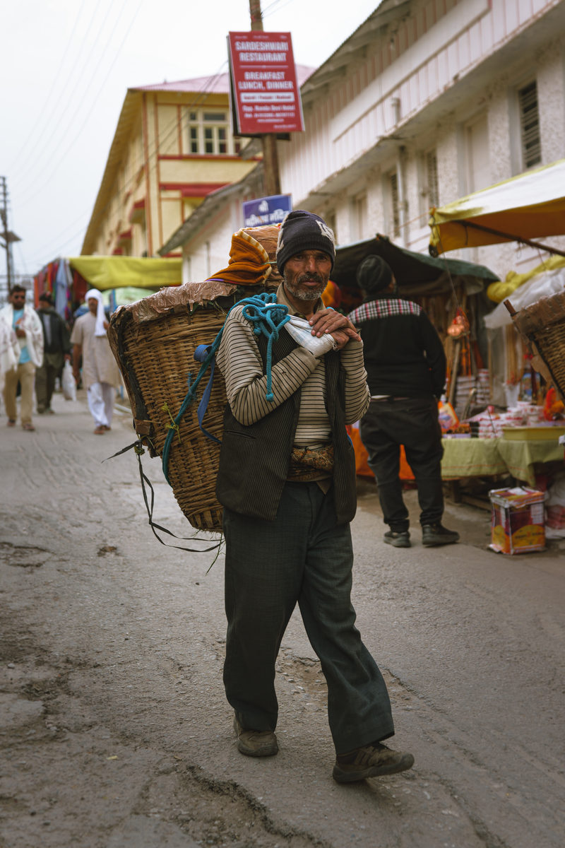 A porter carrying a loaded basket through the market street of a mountain town